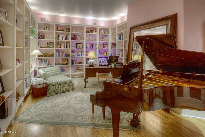 Piano in pink room with bookshelves