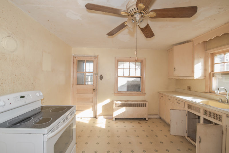 A kitchen with a stove top oven sitting next to a window before remodel