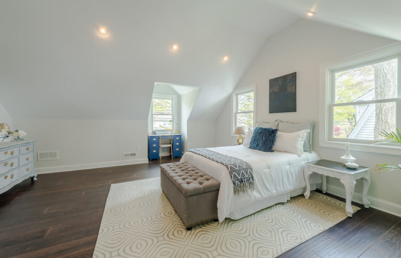 A bedroom with a bed and desk in a room