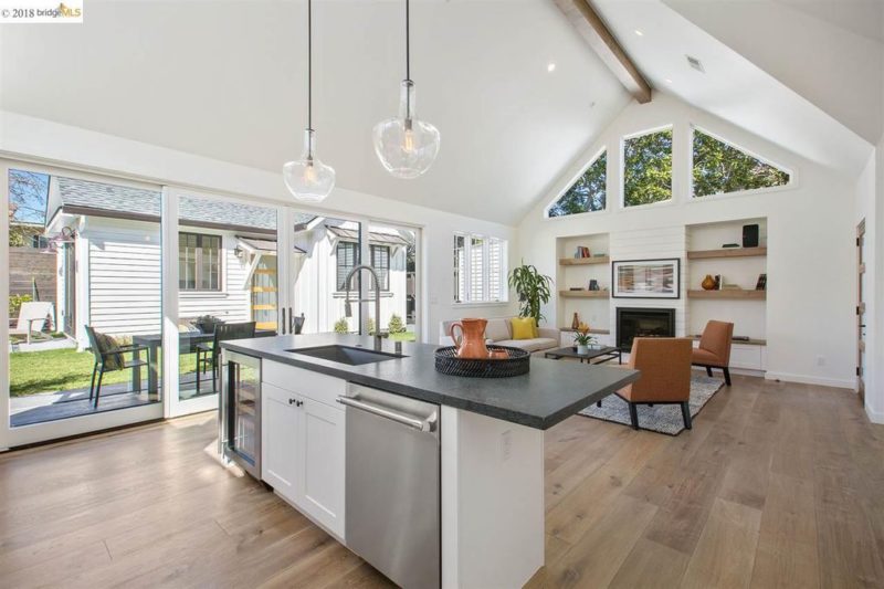 A kitchen with a wood floor open to family room with fireplace