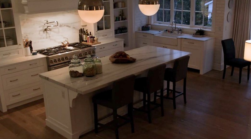 A kitchen with an island with marble countertop