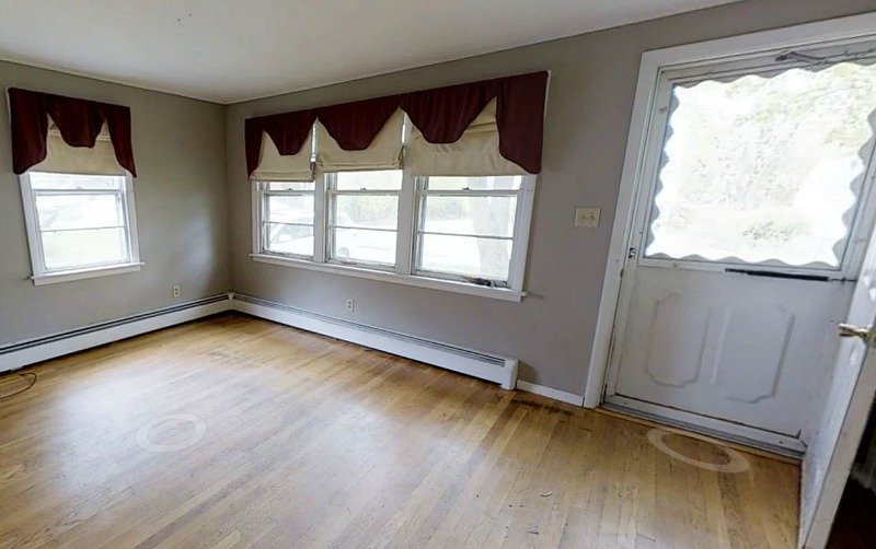 A close up of hardwood floors in empty room with front door before remodel