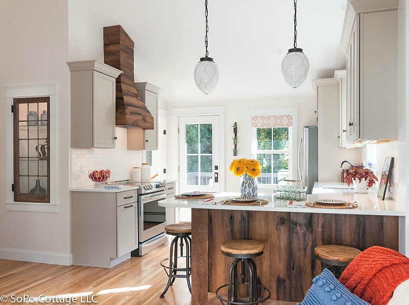 Cottage kitchen after remodel with wood hood over range and wood peninsula