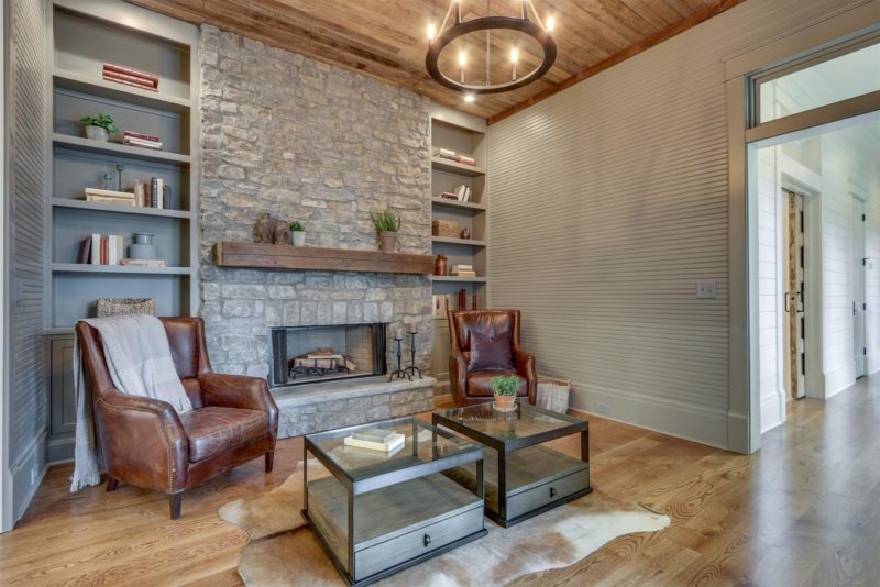 A living room with stone fireplace and two leather chairs