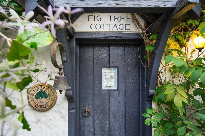 Front door of cottage with sign Fig Tree Cottage above door