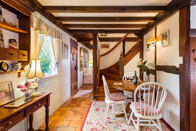 Small table and three chairs in cottage beside twisty staircase