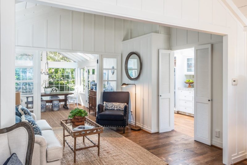 A living room in a Carmel cottage with board-and-batten walls painted white