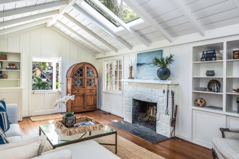 Living room with skylight, white walls, and fireplace