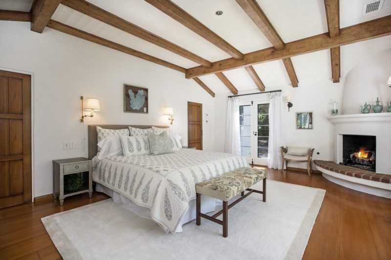 A bedroom with a bed and beamed ceiling