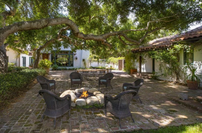 Fire pit and chairs on brick patio behind house