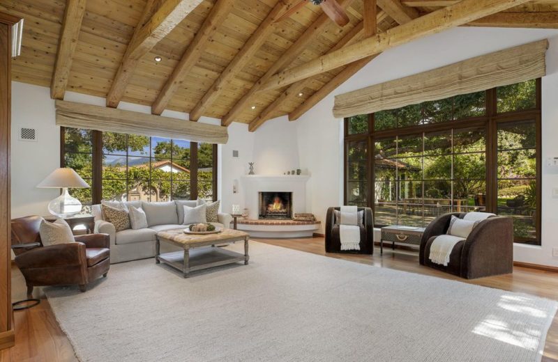 A living room filled with furniture and a large window and fireplace in the corner