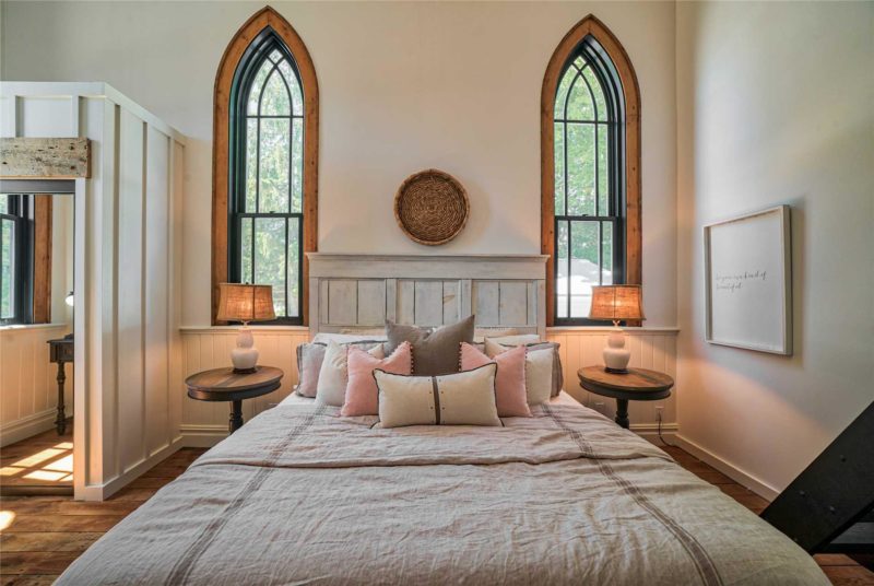 Bed between two tall windows in converted church