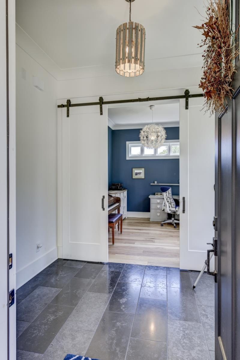 Entry hall of modern farmhouse with barn doors leading to study