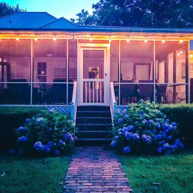 Back exterior of screened porch with door with hydrangeas