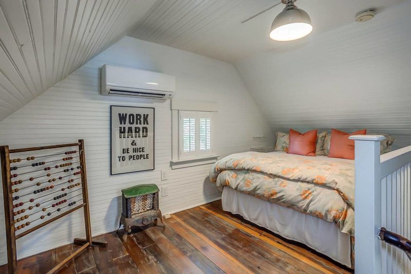 A bedroom with shiplap walls and hardwood floor