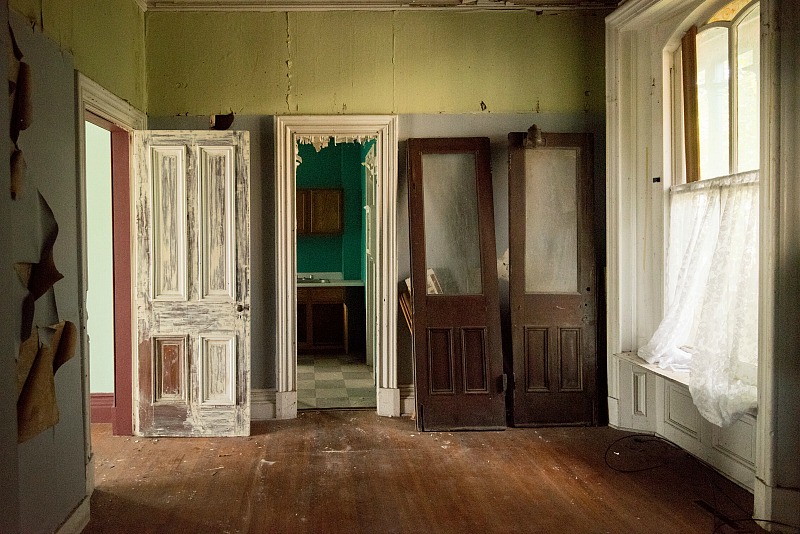 Unattached doors leaning against wall inside old mansion