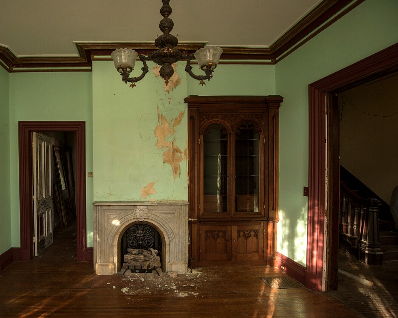 Living room with fireplace, built-ins, and vintage light fixture inside mansion