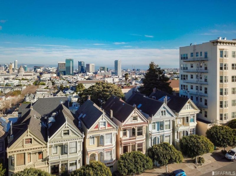 Aerial view of colorful row of Steiner Street houses with city in background