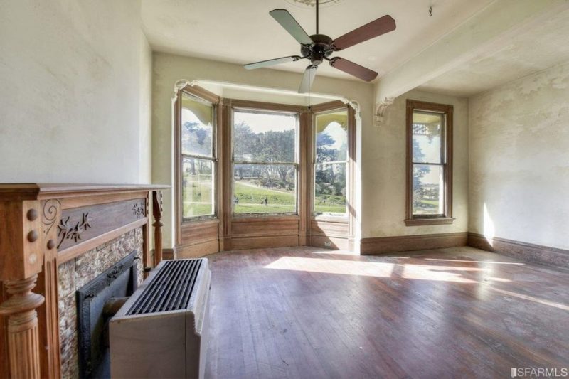 An empty room with a fireplace and a large bay window