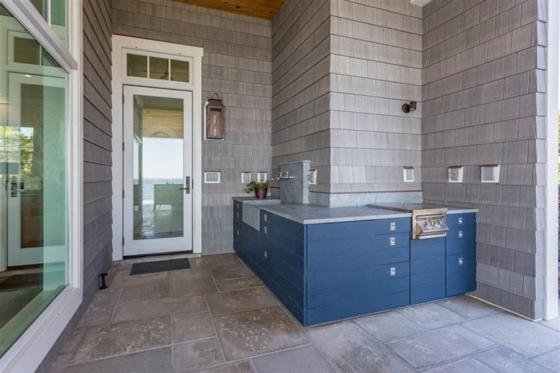 Back door and outdoor kitchen with blue cabinets behind beach house