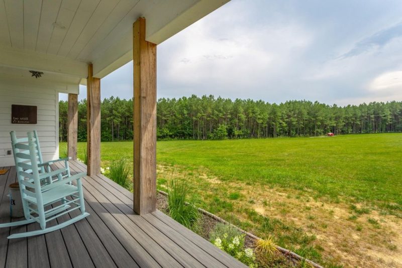 farmhouse porch overlooking yard and line of trees