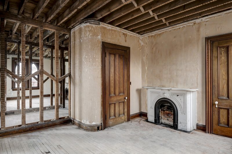 Unfinished room with a wooden closet door and vintage fireplace