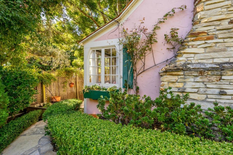 exterior corner of pink cottage with shutters