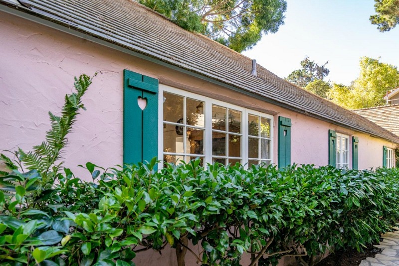 front of pink cottage in Carmel with shutters